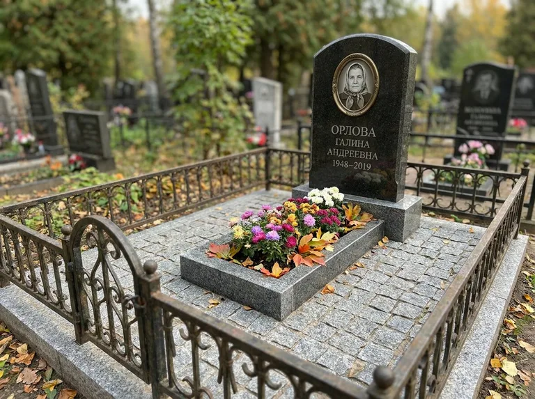 Благоустроенное захоронение с гранитной плиткой, оградой и цветником в Сургуте