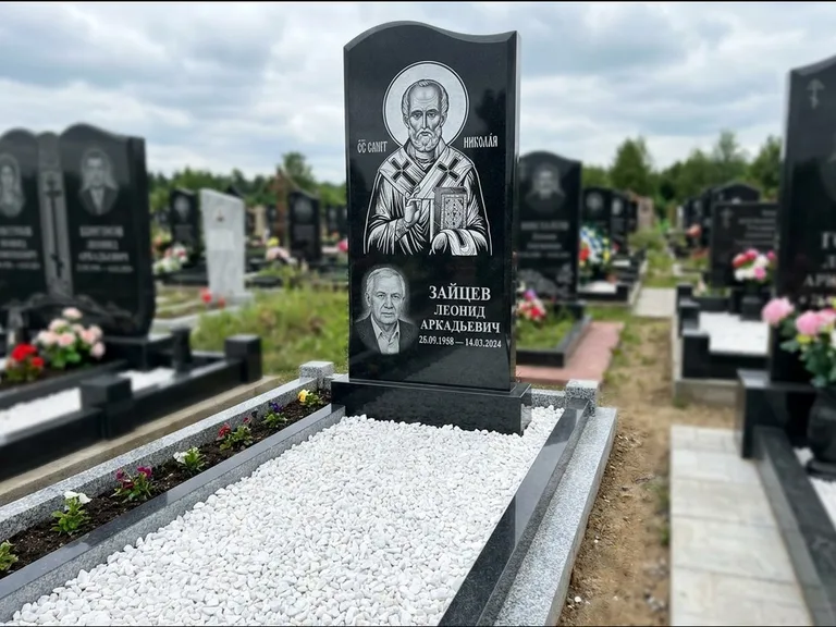 Памятник с гравировкой иконы: стела с крестообразным навершием — икона в резной рамке-киоте, газон без ограды, стриженая трава, работа «Раевская» в Сургуте