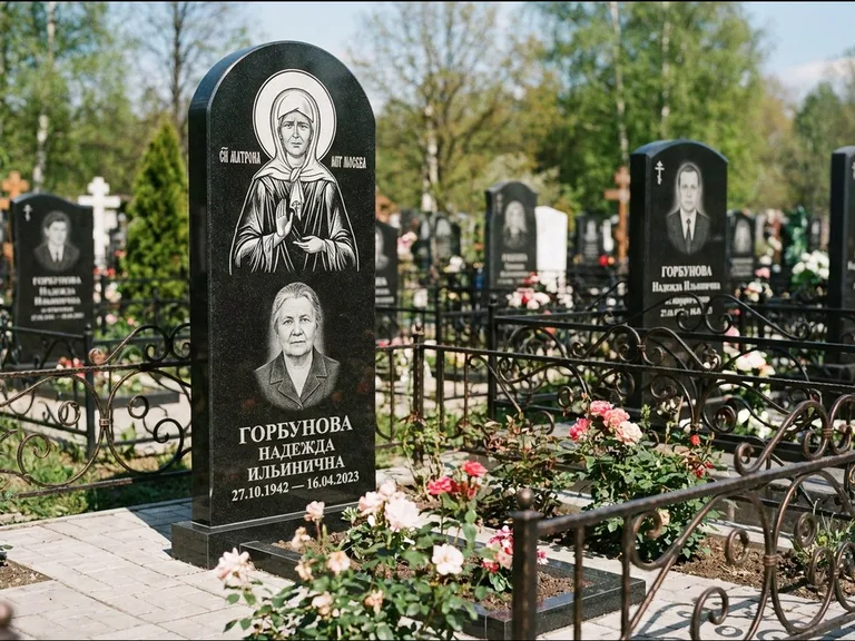 Памятник с гравировкой иконы: стела с арочным верхом и киотом под образ — гравировка образа Матроны Московской, гранитный цоколь с тёмной плиткой, работа «Ковалёв» в Сургуте