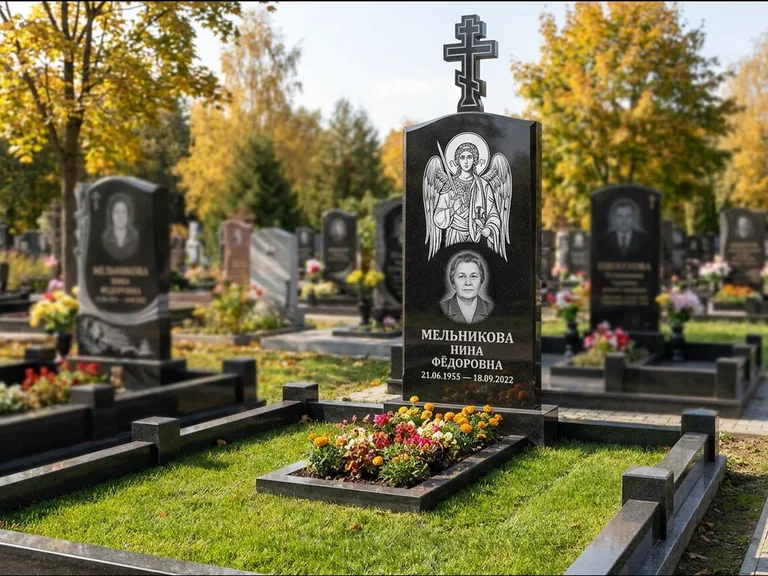 Памятник с гравировкой иконы: округлая стела-медальон с ликом — гравировка Богородицы «Семистрельная», луговые травы и полевые цветы за участком, работа «Гущин» в Сургуте