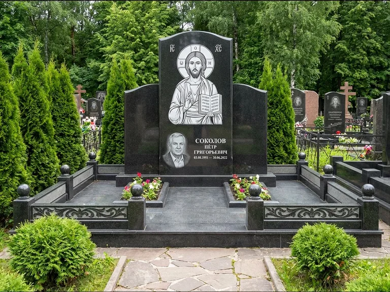 Памятник с гравировкой иконы: широкая горизонтальная лежачая плита-стела — икона в резной рамке-киоте, серая гравийная отсыпка с бордюром, работа «Богданова» в Сургуте
