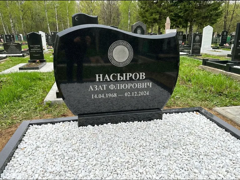 Мусульманский памятник: стела с волнообразным скошенным верхом — гравировка мечети под полумесяцем и звёздами, белая мраморная крошка с бордюром, работа «Насыров» в Сургуте