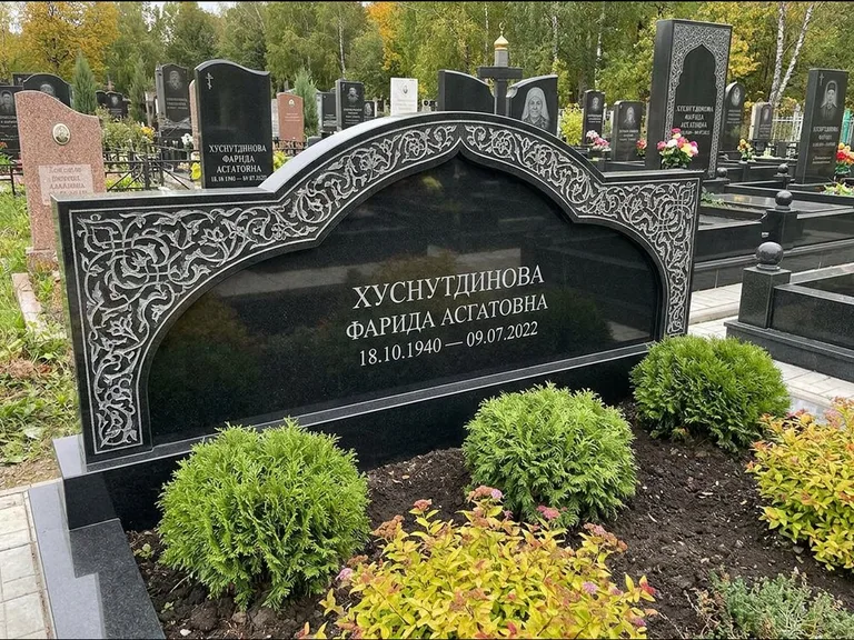 Мусульманский памятник: вытянутая горизонтальная семейная стела с аркой — белая гравировка силуэта мечети с минаретами, участок с декоративными кустами, работа «Зарипова» в Сургуте