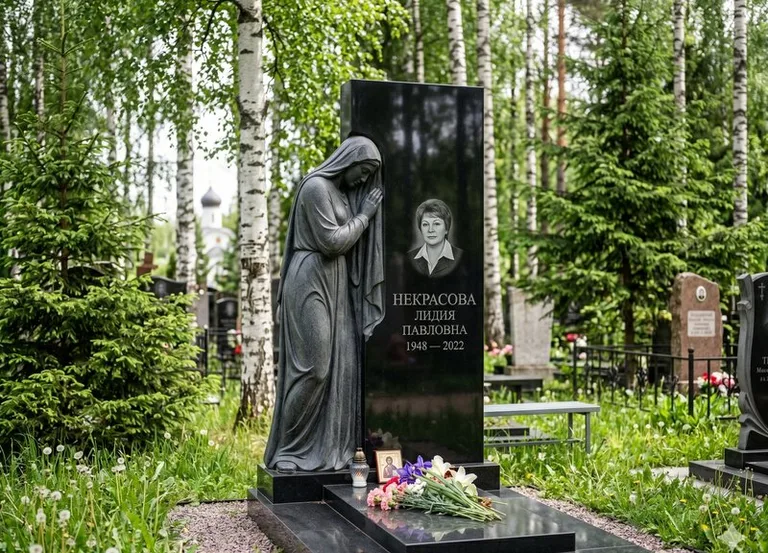Гранитная фигура скорбящего мужчины у чёрной стелы в Сургуте